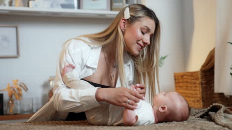 beautiful young mom talking to her newborn son. mother holds little hands of a baby and leans to kiss her child.