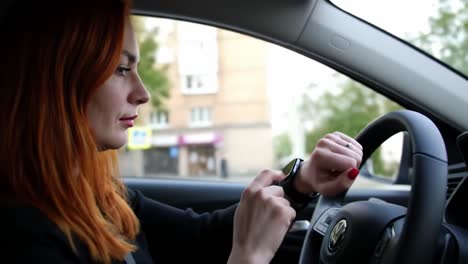 a focused young woman driving while monitoring her smartwatch, showcasing modern technology and daily life in urban environments