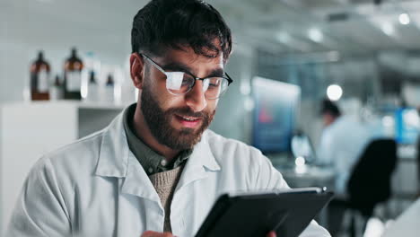 a male scientist in a lab coat working on a tablet