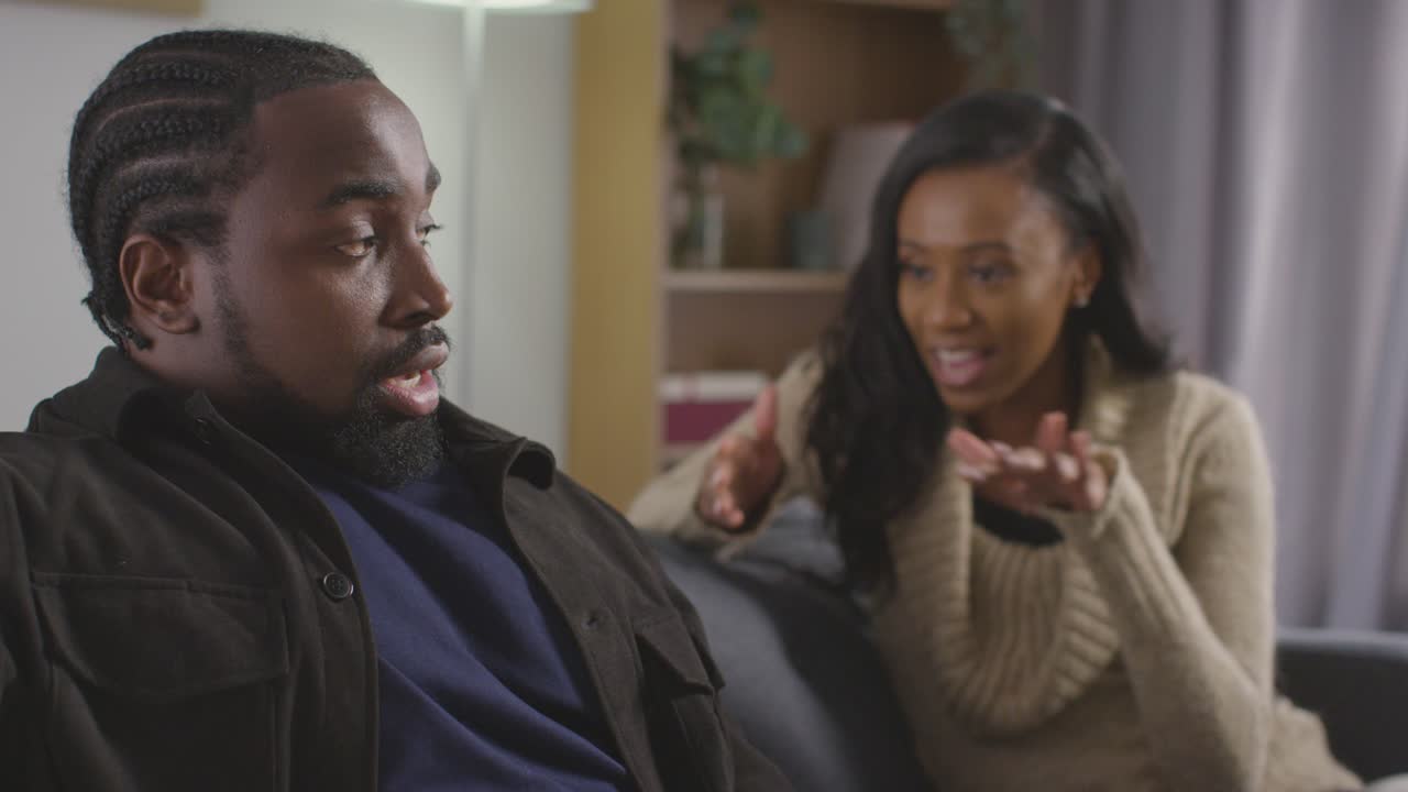 Close Up Of Couple At Home Sitting On Sofa In Lounge Having Break Up Argument