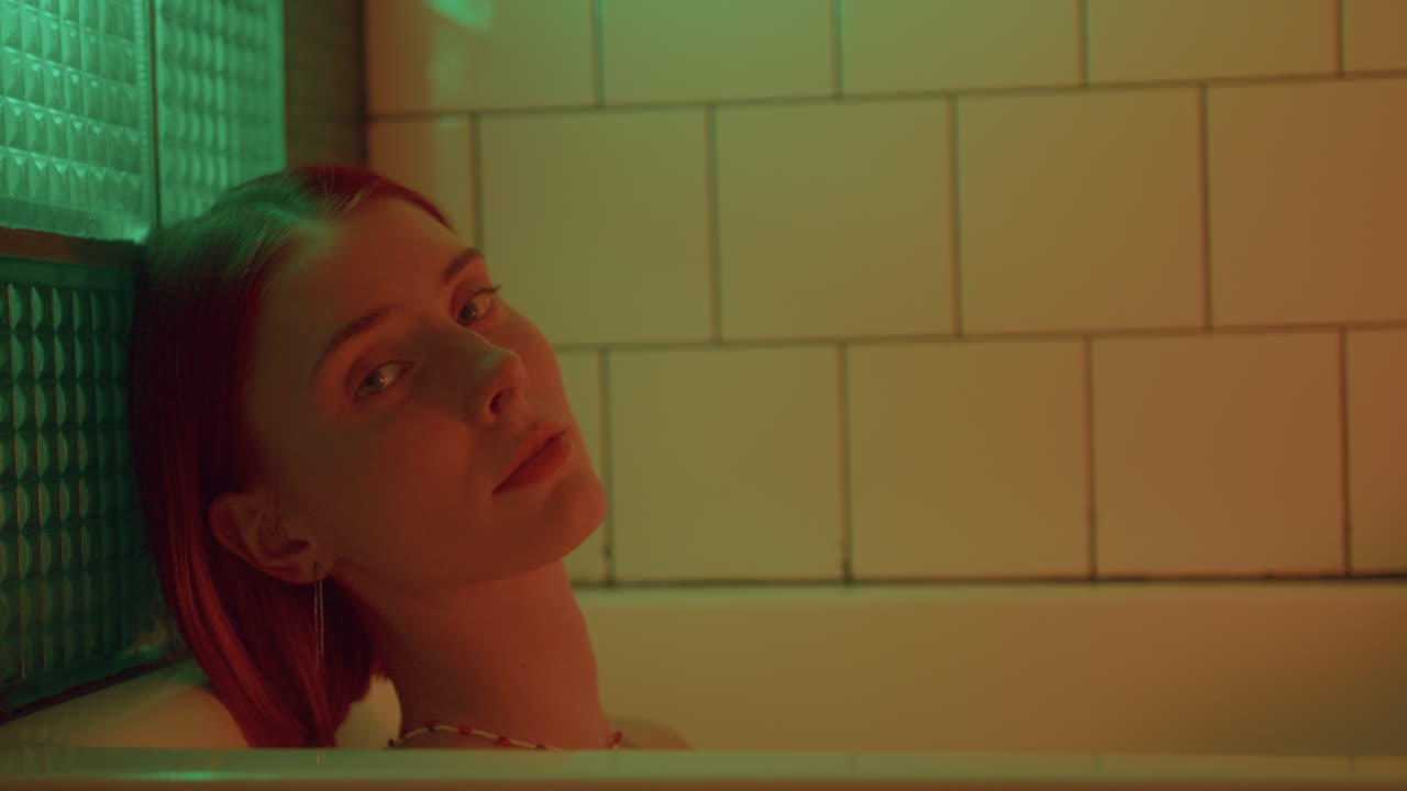 다채로운 빛으로 조명된 욕조에서 휴식을 취하는 아름다운 여성의 초상화