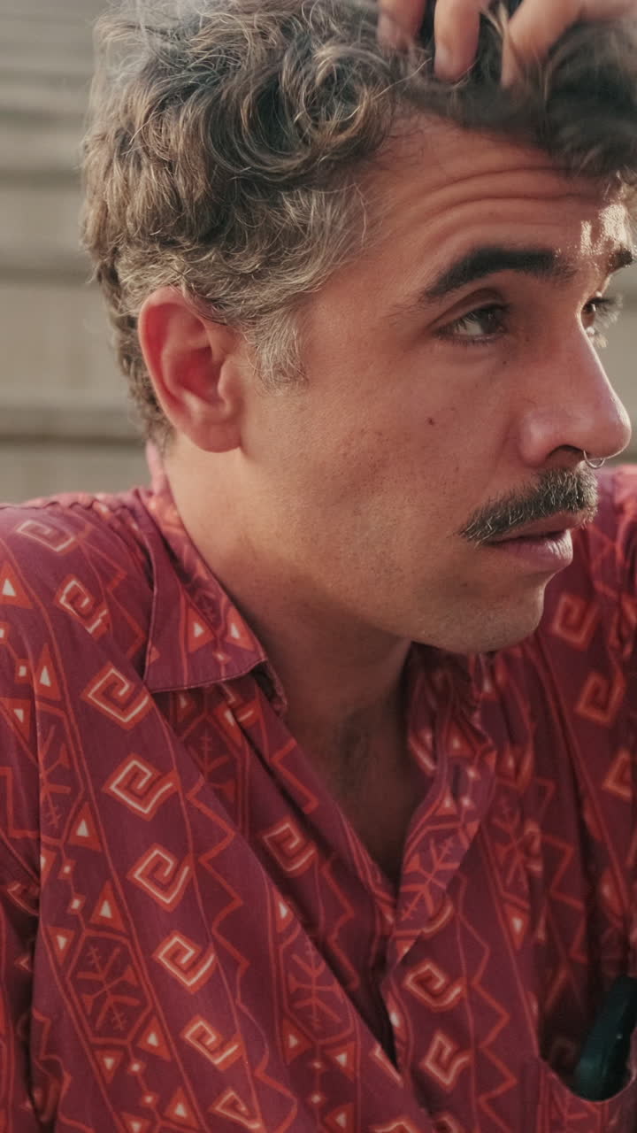 Close-up Portrait of a Thoughtful Young Man with Curly Hair and Mustache