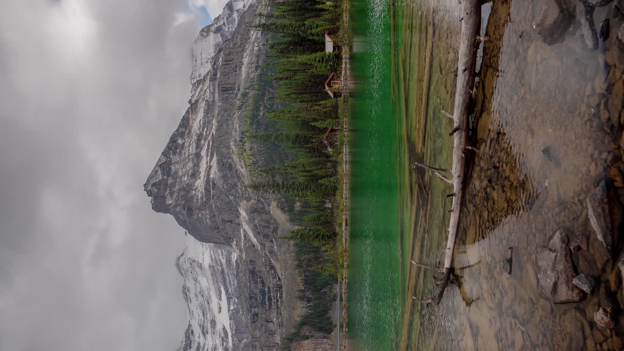 lapso de tiempo vertical de 4k, nubes dramáticas que se mueven sobre picos nevados y aguas cristalinas del lago