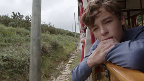 teenage boy on a train journey through scenic mountains