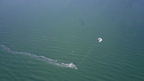 Drone-shot-of-a-kiteboarder-surfing-on-the-coast-of-Ilha-do-Guajiru,-Brazil