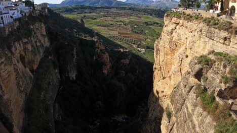 Inclinación-Aérea-Hacia-Arriba-Del-Río-Del-Valle-Con-Tierras-De-Cultivo-De-Alimentación-De-Agua-En-Ronda-España