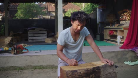 indonesian wood carver draws a sketch of balinese traditional mask on the block of wood