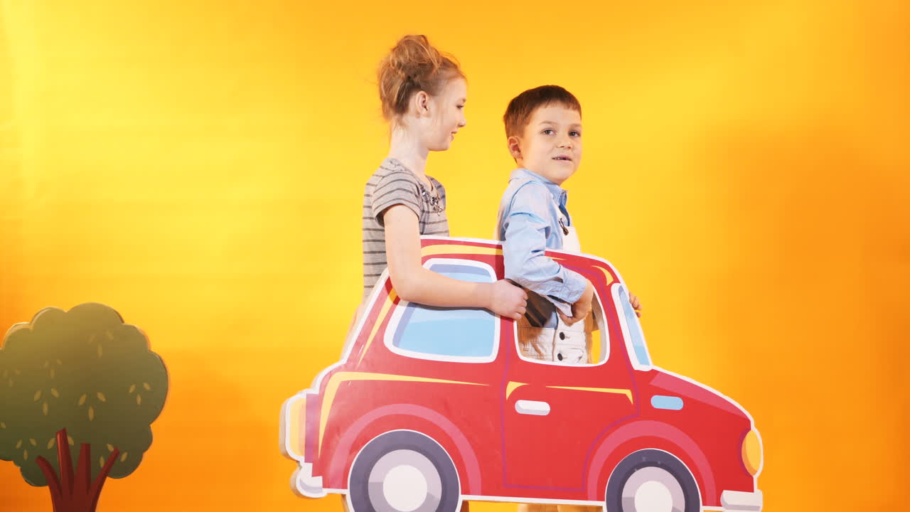 Anak-anak Ceria dengan Mobil Mainan Besar Berlatar Dinding Kuning Cerah. Suasana Anak-anak di Studio
