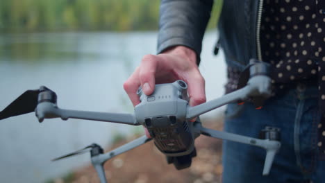 la mano caucásica presiona y mantiene el botón en la parte trasera de un dron para encenderlo