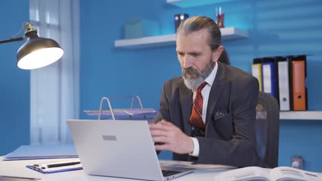 hombre maduro de mediana edad trabajando en una computadora portátil en su oficina con atención y concentración.