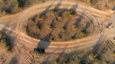 Schwarzes-Auto,-Das-An-Einem-Sonnigen-Tag-Auf-Einem-Unbefestigten-Kreisverkehr-Fährt