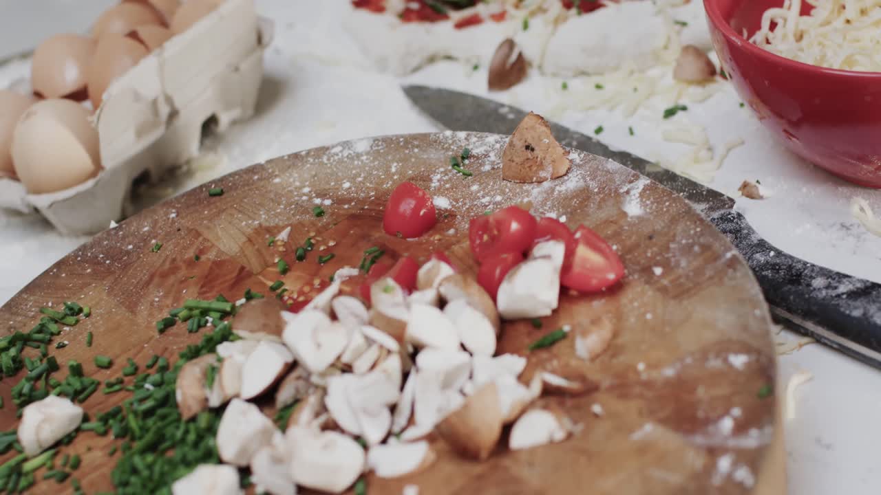 primer plano de queso y verduras en la masa de pizza con equipos de cocina en cámara lenta