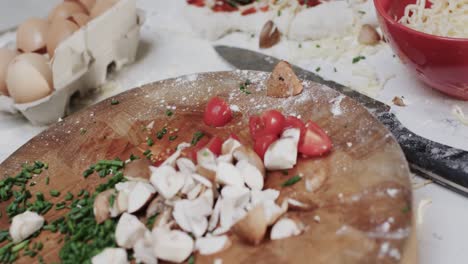 primer plano de queso y verduras en la masa de pizza con equipos de cocina en cámara lenta