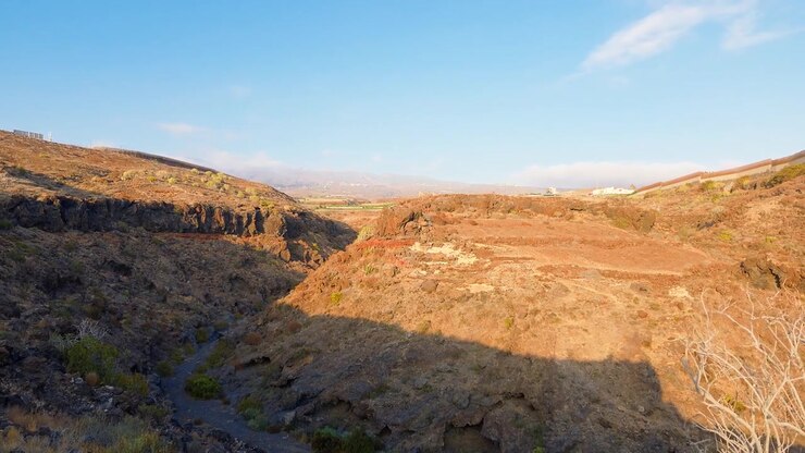 Ampia vista di un paesaggio di gola rocciosa e arida sotto un cielo azzurro limpido alla luce del primo mattino