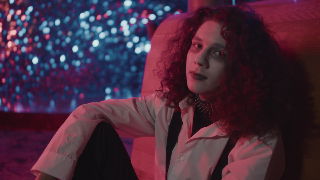 바닥에 앉아서 카메라를 쳐다보는 젊은 남자.