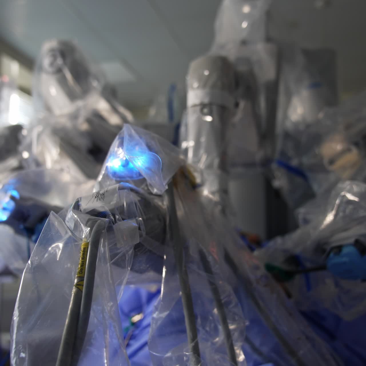 Blue lights on the tops of robotic arms in surgeon machine. Da Vinci surgery system carry out the operation. Close up. Blurred backdrop