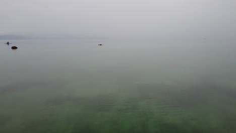 Flyby-an-outrigger-boat-while-fish-are-splashing-the-water-in-Cebu,-Philippines,-Asia,-Drone,-Aerial