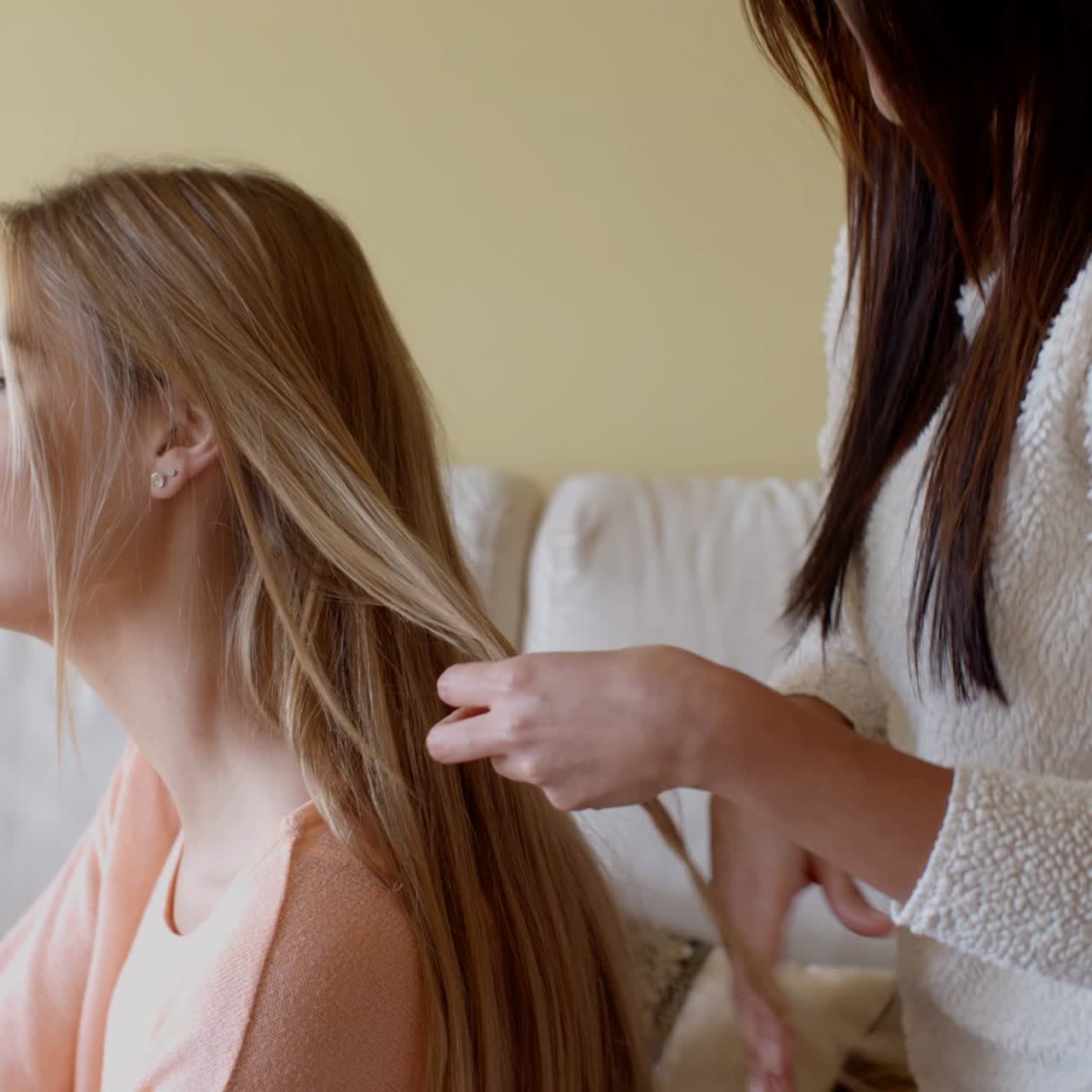 Mujer guapa con una amiga arreglándose el cabello rubio