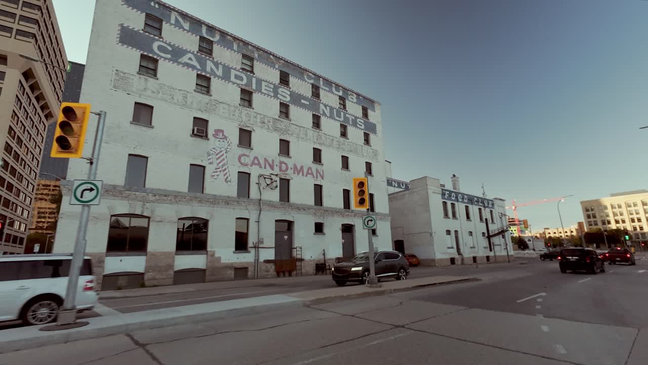 POV shot from car driving toward downtown Winnipeg, passing under train bridge with moving train