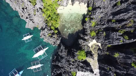 people swimming at secret beach of el nido in a tropical lagoon hidden behind rock cliffs with tour boats at entrance