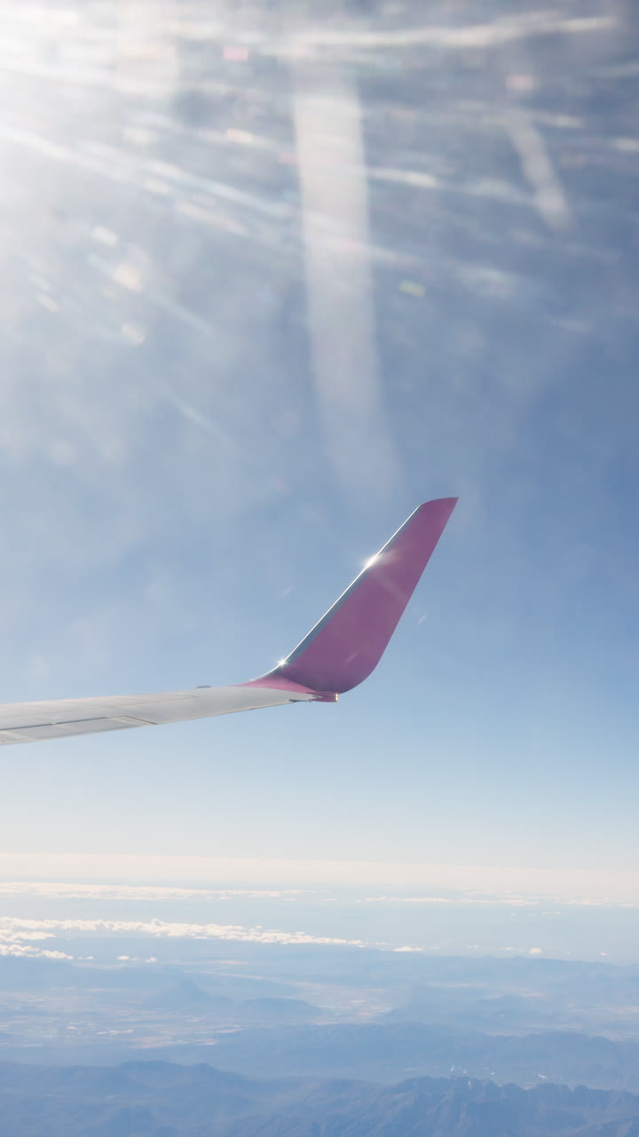 View from airplane window of the sky, clouds, and mountains