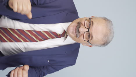 Vertical-video-of-Old-businessman-making-cute-gestures-to-the-camera.