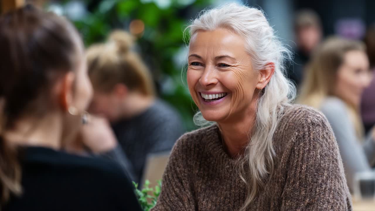 A Joyful Exchange: Capturing the Delightful Moment Between Two Friends Sharing Laughter and Lively Conversation Over Coffee in a Cozy, Greenery-Filled Café Setting