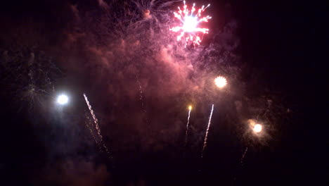 rayos brillantes de luz llenan el cielo nocturno y explotan en un colorido espectáculo de fuegos artificiales