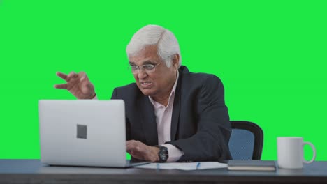 stressful senior indian manager working on laptop green screen