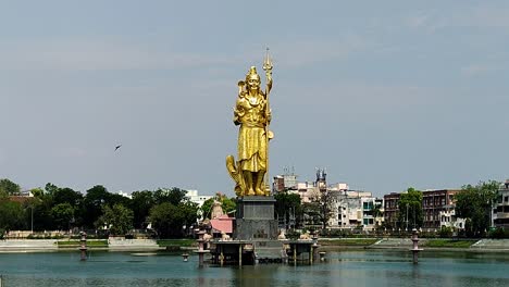 majestic golden lord shiva statue rising from sursagar lake, vadodara. divine symbol of spirituality, devotion and indian cultural heritage amid city backdrop.