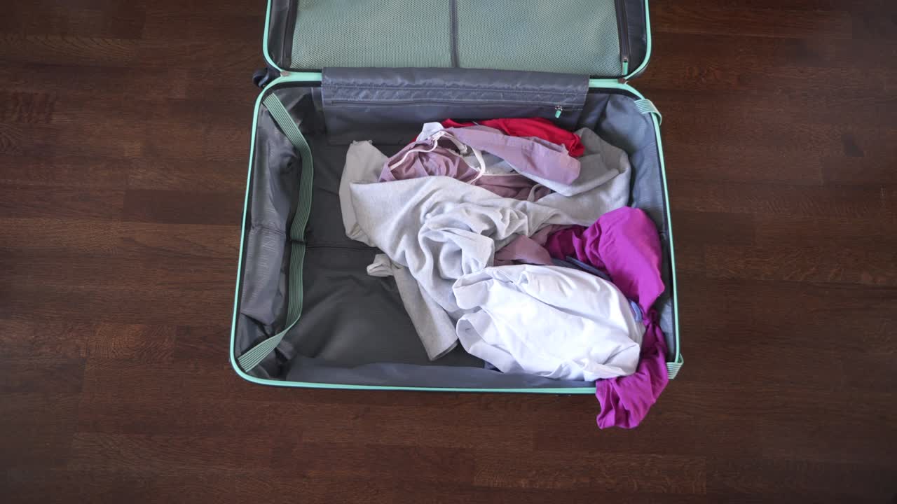 Woman quickly throwing and packing travel suitcase