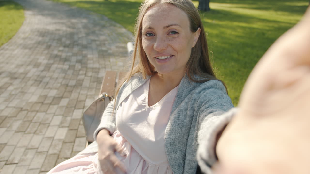 임신 한 여자 가 공원 에서 셀피 를 찍고 있다