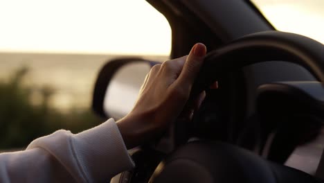 woman with nude manicure driving a car along the coast