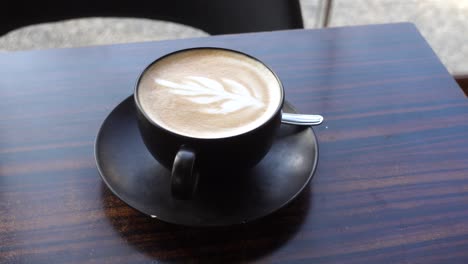 a cup of latte art on a wooden table