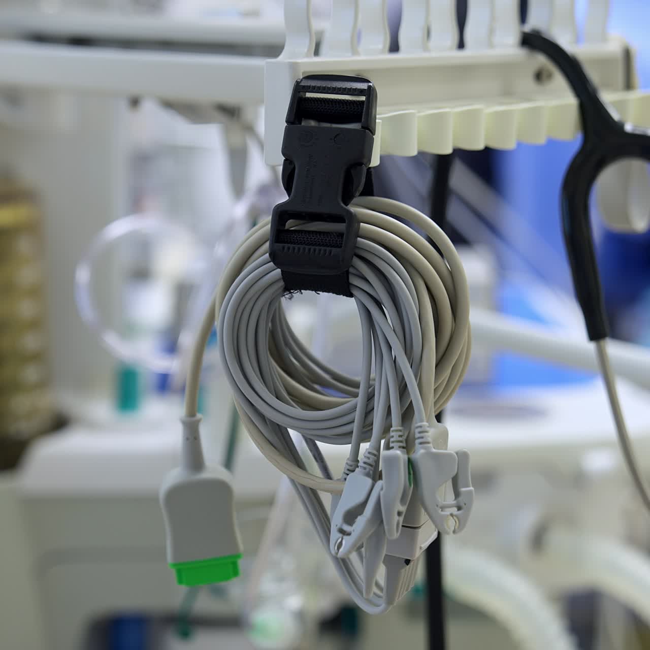 Folded wires from medical equipment and stethoscope hanging in the surgical room. Air pumping machine working at backdrop in blur