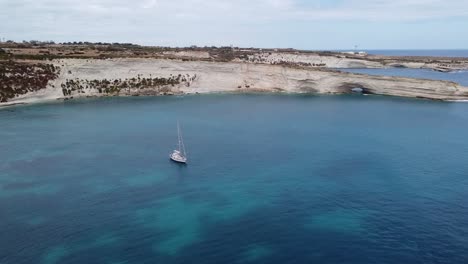 drone view over a boat and the cliffs on malta island