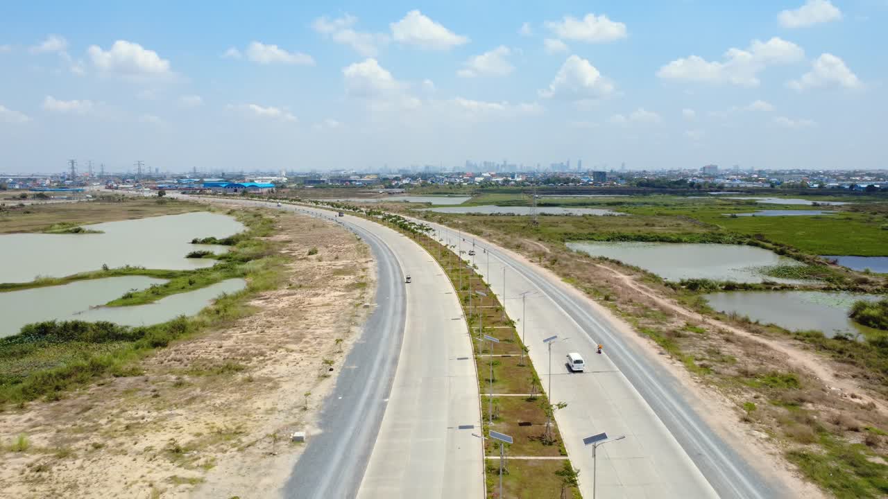 Newly built road connecting Techo International Airport in Kandal Province with Phnom Penh cityscape at distance, Drone shot, Establishing shot