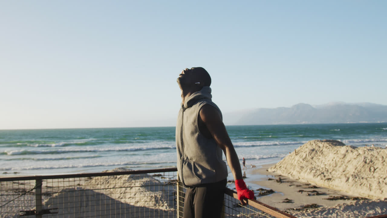 Focused african american man taking break in exercise outdoors by the sea