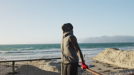 Focused-african-american-man-taking-break-in-exercise-outdoors-by-the-sea