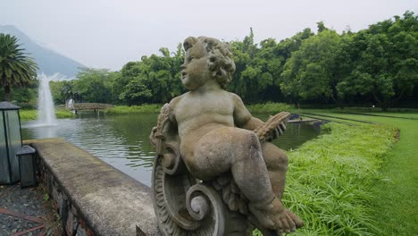 a stunning statue of a baby stands in the foreground of a beautifully landscaped area, with a volcano visible in the far distance