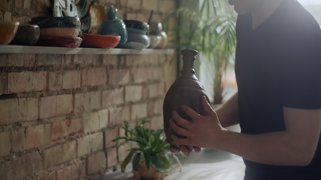 Man holding a handmade clay vase in a pottery studio