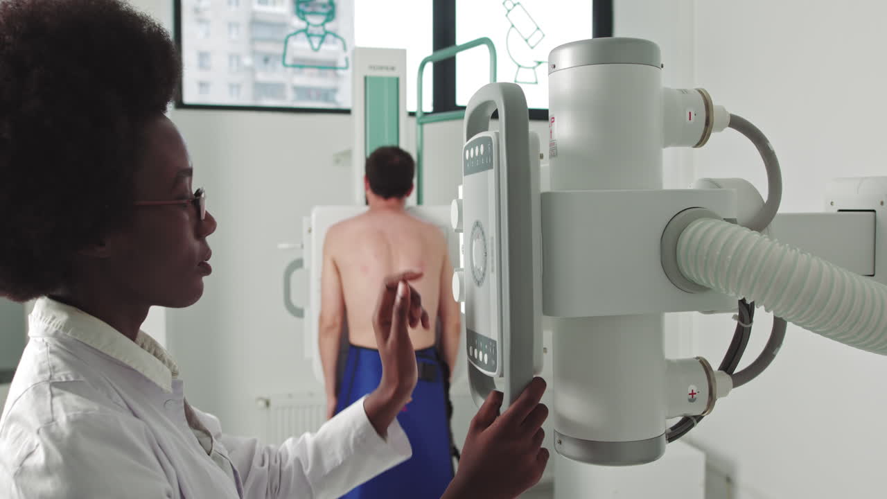 Female technician adjusts xray machine in medical cabinet scanning for fractures and broken limbs in