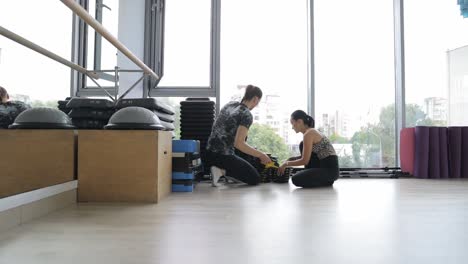 focused woman checks her phone while preparing for workout at a modern gym a dedicated woman stands in a spacious gym checking her phone while next to a set of weights sunlight streams in creating an energetic atmosphere as she prepares to start her fitness routine