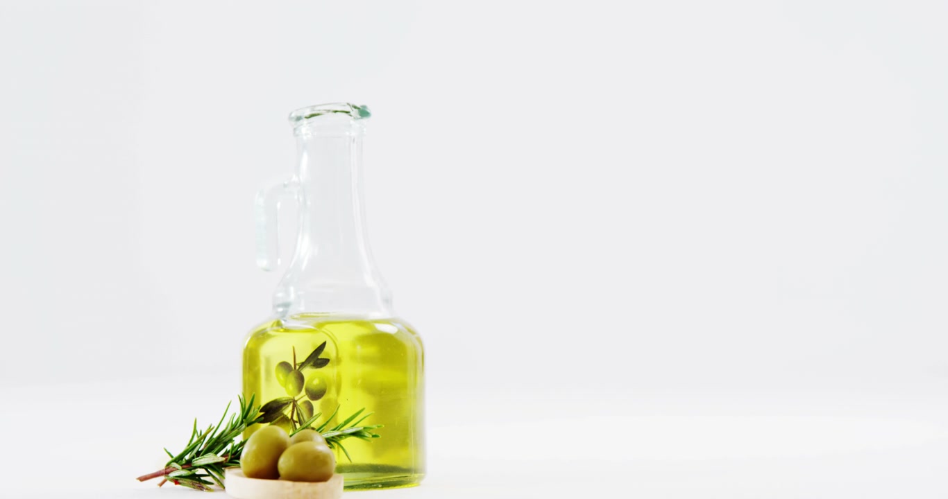 Erbe aromatiche, olive verdi e olio d'oliva su sfondo bianco
