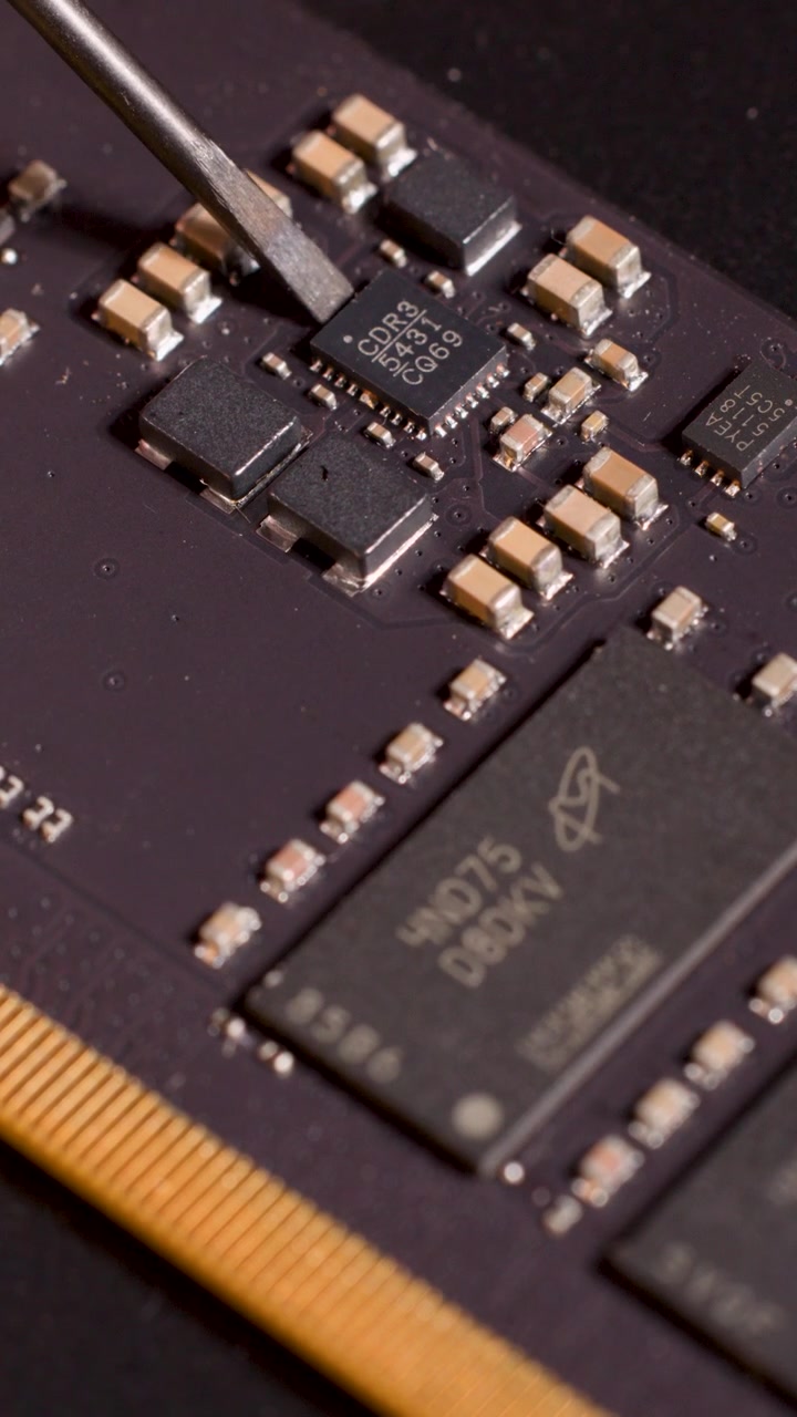Metalværktøj angiver præcist mikrochip på printplade under skarpt, fokuseret lys, makroperspektiv