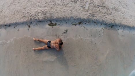 hombre tendido en la orilla de la playa