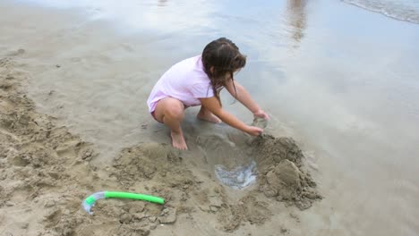 girl playing on the beach building sand castle-2