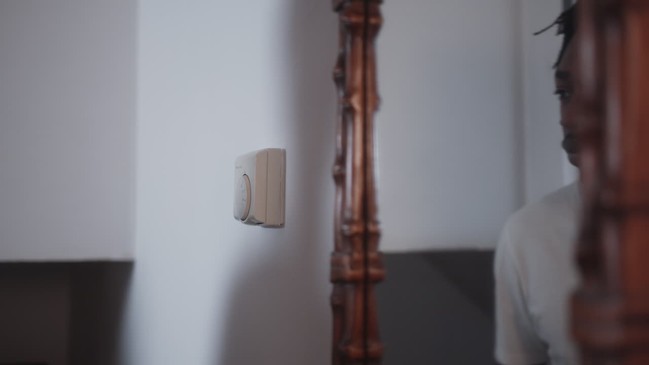 hombre ajustando el termostato para bajar la temperatura para ahorrar en facturas de energía durante la crisis del costo de la vida de cerca