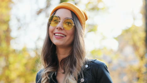 vista cercana de una joven mujer caucásica con gafas de sol y gorro mirando a un lado