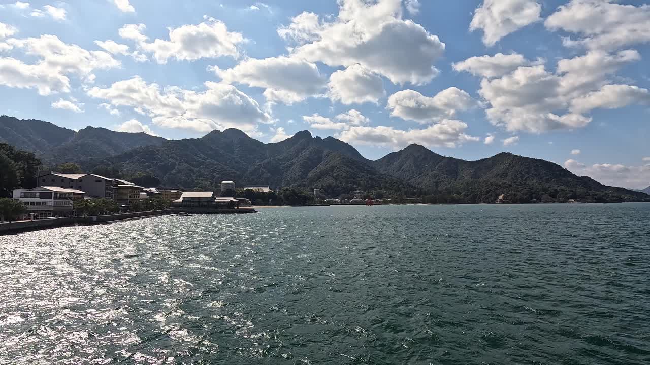 Scenic Ferry View of Miyajima Island’s Mountainous Coastline and Sparkling Hiroshima Bay Waters on a Sunny Day in Japan